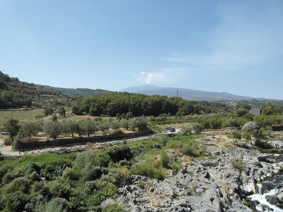 Il letto roccioso dell'Alcantara fra gli ulivi, con l'Etna sullo sfondo